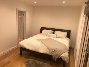 um quarto com uma cama com lençóis brancos e almofadas em Redhill Lodge em Farnham