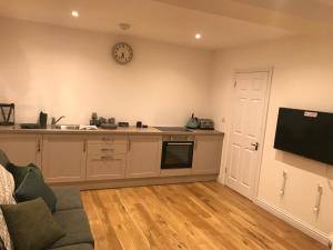 a living room with a kitchen and a tv at Redhill Lodge in Farnham