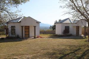 una pequeña casa blanca con un árbol en el patio en Khutsong Lodge, en Acornhoek