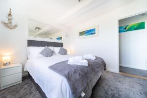 a bedroom with a large white bed and a night stand at Newquay Sunset & Sea View Apartment in Town Centre in Newquay