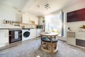 a kitchen with a table and a sink and a stove at Newquay Sunset & Sea View Apartment in Town Centre in Newquay
