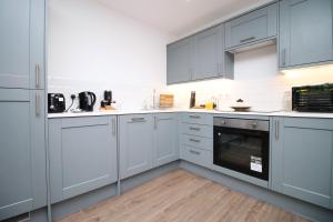 a large kitchen with white cabinets and appliances at Casa di pietra - Cardiff City centre apartment with patio, Free private parking in Cardiff
