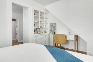 a white bedroom with a bed and a desk at Satoshi Hideout Sol Apartments in St. Petersburg