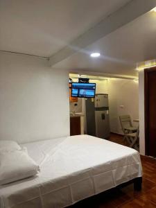 una camera con letto bianco e una cucina di Acogedor Apartaestudio Tricentenario Medellín a Medellín