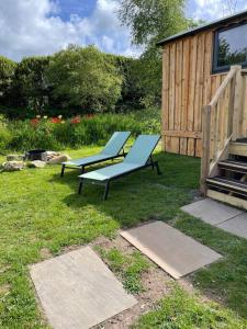 two blue benches sitting in the grass next to a building at Pembrokeshire Shepherd hut with hottub in Jordanston