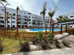 a large apartment building with a swimming pool and palm trees at PUSHE Playa Granada Beach & Golf 21 in Motril