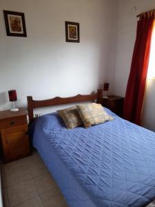 a bedroom with a blue bed with two pillows on it at Cabañas Aliksir in Cosquín