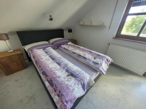 Un dormitorio con una cama con sábanas moradas y una ventana en FeWo Giss, en Postbauer-Heng