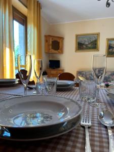 a table with a plate and wine glasses on it at Appartamento del Sole in Borno