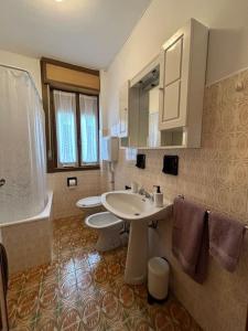 a bathroom with two toilets and a sink and mirror at Appartamento del Sole in Borno