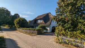 une maison avec un toit de chaume et une allée en briques dans l'établissement Ferienwohnung-im-Gruenen-zwischen-Binz-und-Sellin, à Zirkow