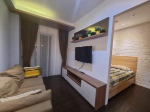 a bedroom with a bed and a tv on a wall at SIGNATURE PARK GRANDE MT.Haryono in Jakarta