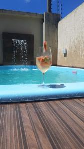 加拉尼溫斯的住宿－CASA COM PISCINA GARANHUNS，游泳池旁的一杯葡萄酒和水果