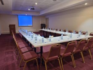 a long table in a room with chairs and a screen at El Sheikh Suites Hotel in Beirut
