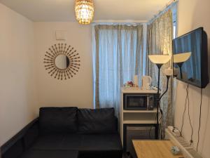 a living room with a black couch and a mirror at TravelStop #Ealing in London