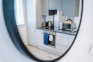 a kitchen with white cabinets and a mirror at Victoria Mill by Staycay in Wigan