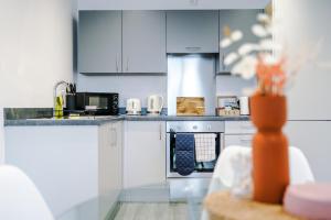 a kitchen with white cabinets and a stove top oven at Victoria Mill by Staycay in Wigan