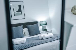 a bedroom with a bed with blue pillows and a mirror at Victoria Mill by Staycay in Wigan