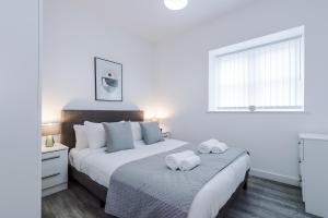 a white bedroom with two beds and a window at Victoria Mill by Staycay in Wigan