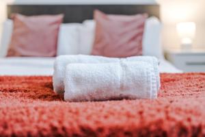 a roll of white towels on a red bed at Victoria Mill by Staycay in Wigan