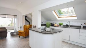 a kitchen with white cabinets and a sink and a window at The Old Piggery in Trefnant