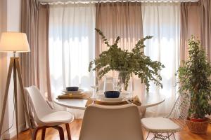 Una mesa de comedor con sillas blancas y una mesa con un jarrón. en Cuencaloft Luxurious, en Cuenca