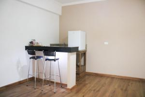 a kitchen with a bar with stools and a refrigerator at VOA Hotel Rezende in Lambari