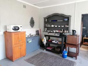 a kitchen with a counter and a shelf with a microwave at Pied Cow Cottage in Hilton