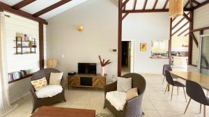 ein Wohnzimmer mit einem Tisch, Stühlen und einem TV in der Unterkunft Villa de charme avec piscine et magnifique vue mer in Les Anses-dʼArlets