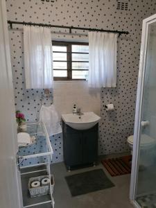 a bathroom with a sink and a toilet and a window at Pied Cow Cottage in Hilton