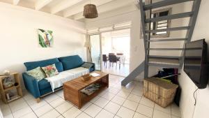sala de estar con sofá azul y escalera en Ti Caraïbes, appartement T3 atypique, vue mer, piscine et proche plage, en Les Trois-Îlets