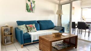 sala de estar con sofá azul y mesa en Ti Caraïbes, appartement T3 atypique, vue mer, piscine et proche plage, en Les Trois-Îlets