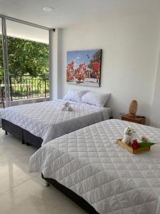 1 dormitorio con 2 camas y ventana grande en AKUAIPPA HOSTAL RESTAURANT, en Santa Marta