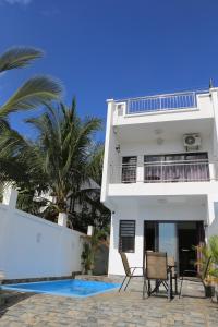une maison blanche avec une piscine et des palmiers dans l'établissement 3 Bedroom Family Pool Villa Flic-en-Flac Beach, à Flic-en-Flac