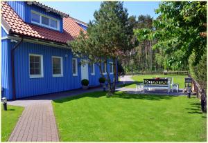 a blue house with a picnic table in a yard at Vila Preila in Neringa