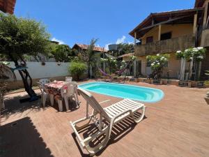 einen Pool mit einem Tisch und Stühlen neben einem Haus in der Unterkunft Toca dos Leões in Algodoal