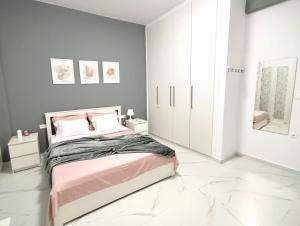 a bedroom with a pink bed and gray walls at FlatFifty in Ierapetra