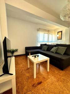 a living room with a black couch and a table at Apartamento soleado para 8 personas en Santoña in Santoña