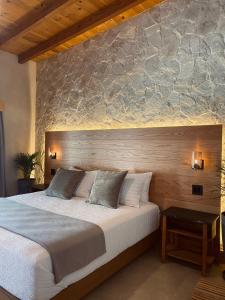 1 dormitorio con 1 cama grande y pared de piedra en MYA Hotel Boutique en Valle de Guadalupe