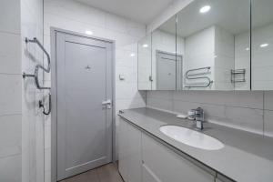 a white bathroom with a sink and a mirror at Bright Kaunas apartment with Castle view in Kaunas