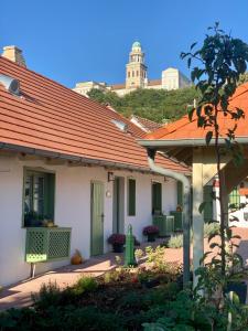 una casa con techo rojo con una colina al fondo en Pannonhalma Várlak Vendégház, en Pannonhalma