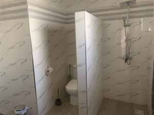 a bathroom with white marble walls and a toilet at Chambre meublée indépendante Les Hirondelles in Ngaparou