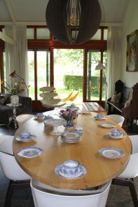 uma sala de jantar com uma mesa de madeira com pratos em Familiehuis De Betuwe met prive kunstgras tennisbaan en sauna em Erichem