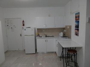 een witte keuken met een wastafel en een koelkast bij Stelia's Seagate Studio Apt. in Larnaka