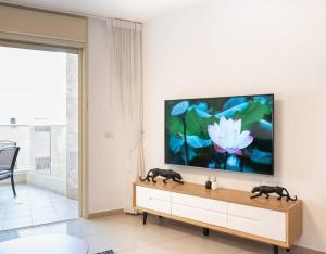 a living room with a flat screen tv on a wall at Neat 4BR Apt. With Parking/High Floor/Elevator/AC in Rishon LeẔiyyon