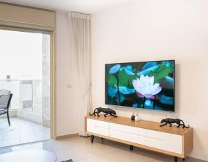 里雄莱锡安Neat 4BR Apt. With Parking/High Floor/Elevator/AC的客厅墙上有一台平板电视