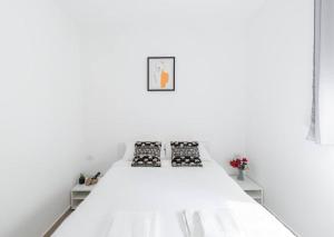 uma cama branca num quarto branco com 2 almofadas em Neat 4BR Apt. With Parking/High Floor/Elevator/AC em Rishon LeZion