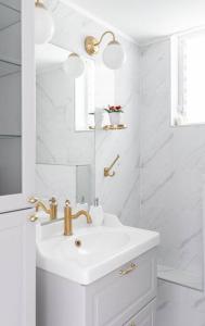uma casa de banho branca com um lavatório e um espelho em Neat 4BR Apt. With Parking/High Floor/Elevator/AC em Rishon LeZion