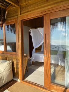 um quarto com uma cama e uma porta de vidro em Pousada D'Oxum Caraíva em Caraíva