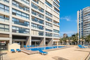 um edifício de apartamentos com piscina e espreguiçadeiras em Santa Margarita 15-E Apartment Levante Beach em Benidorm